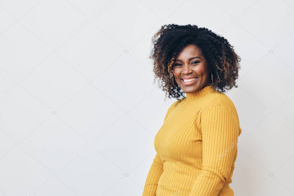 Cheerful woman with frizzy hairstyle  against white background. Smiling. Looking at camera