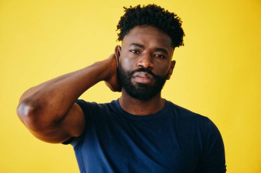 Sarı arka planda elleri saçı olan yakışıklı Afro adamın portresi.