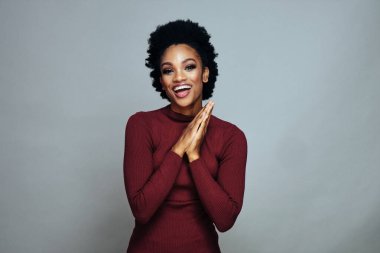 Gülümseyen genç bir Afrikalı Amerikalı kadının portresi ellerini yanağına dayıyor.