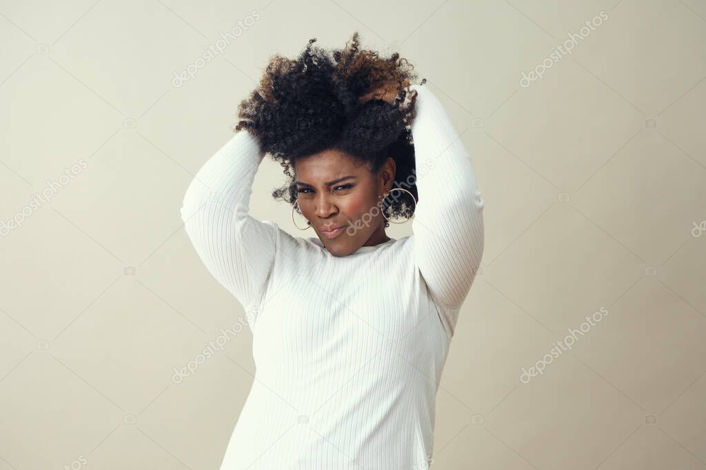 Cheerful Afro woman with hands in hair smiling against white background