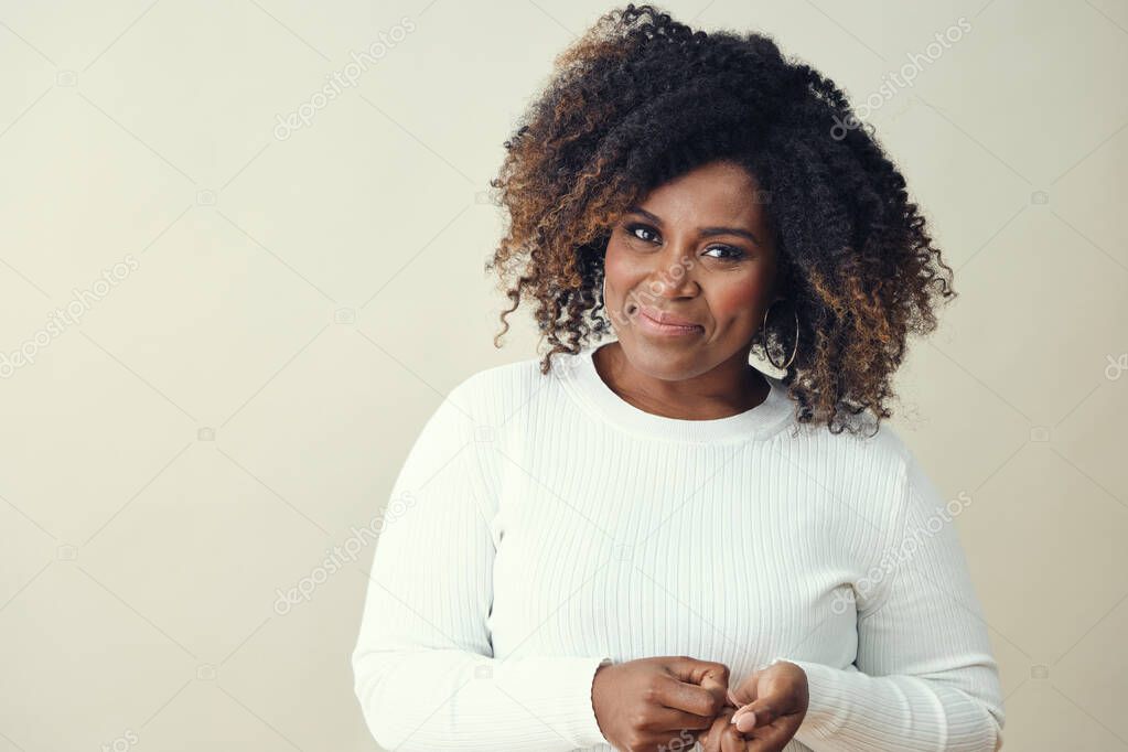 Smiling Afro woman with brown highlights on curly hair looking at camera against white background