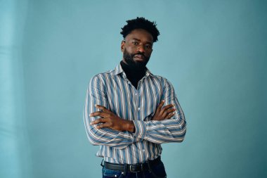 Mavi arka planda mavi gömlekli yakışıklı bir Afro-Amerikan 'ın portresi.