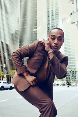 Modern şehir arka planında poz veren yakışıklı Afro-Amerikan adam.