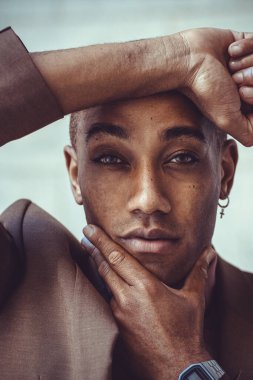 Beyaz fayansın arka planında poz veren yakışıklı Afro-Amerikan adam.