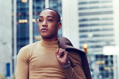 Modern şehir arka planında poz veren yakışıklı Afro-Amerikan adam.
