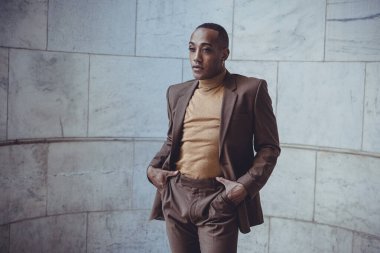 Beyaz fayansın arka planında poz veren yakışıklı Afro-Amerikan adam.