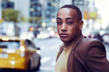 Modern şehir arka planında poz veren yakışıklı Afro-Amerikan adam.