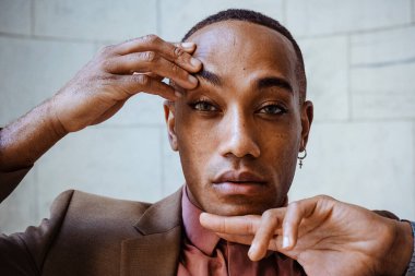 Beyaz fayanslarda poz veren takım elbiseli yakışıklı Afro-Amerikan adam.