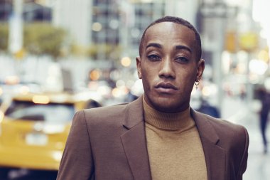 Modern şehir arka planında poz veren yakışıklı Afro-Amerikan adam.