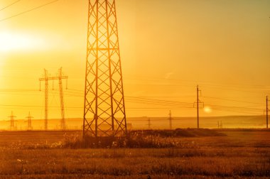 Yüksek gerilim enerji nakil hattı. Enerji ayağı. Gün batımında,