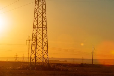 Yüksek gerilim enerji nakil hattı. Enerji ayağı. Gün batımı, şafakta. Elektrik
