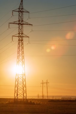 Yüksek gerilim enerji nakil hattı. Enerji ayağı. Gün batımı, şafakta. Elektrik