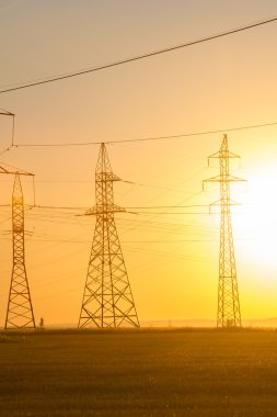Yüksek gerilim enerji nakil hattı. Enerji ayağı. Gün batımı, şafakta. Elektrik