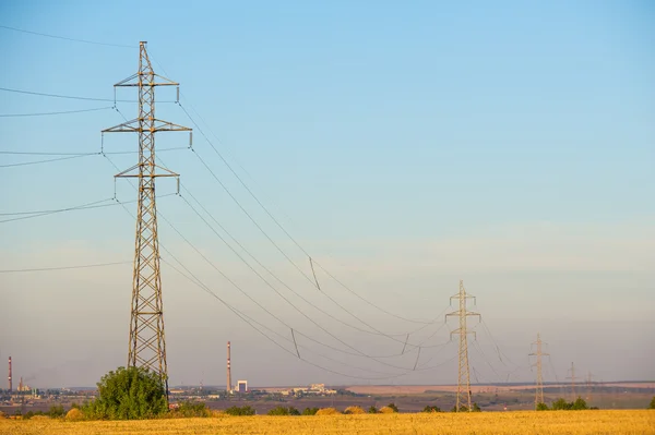 High-voltage power transmission line. Energy pillars. At sunset, — Stock Photo, Image