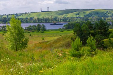 Yaz manzarası, nehir taşkınları, pitoresk kıyılar, kır çiçekli parlak yeşil çimenler, beyaz bulutlu mavi gökyüzü, ılık yaz günleri.,