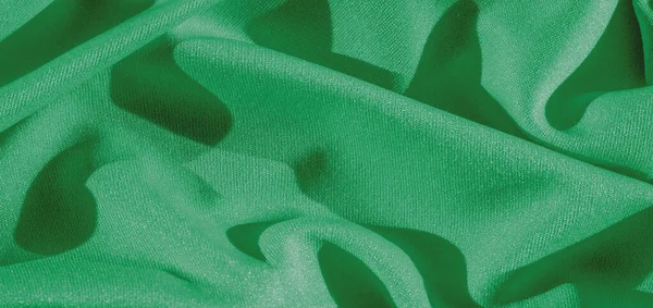 green silk. Smooth elegant green luxury silk fabric can be used as abstract background with copy space, close up. colorful texture