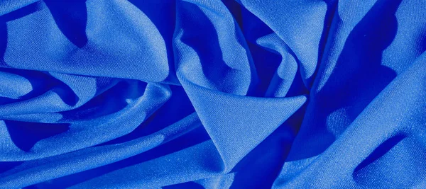 blue silk. Smooth elegant blue luxury silk fabric can be used as an abstract background with copy space, close-up. colorful texture