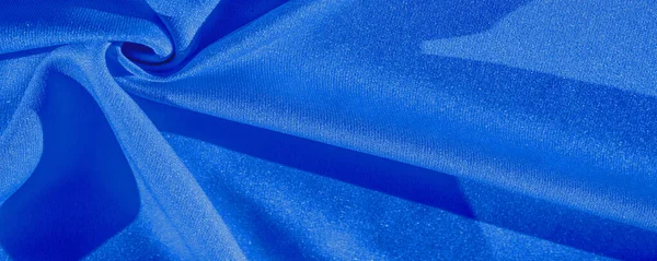 blue silk. Smooth elegant blue luxury silk fabric can be used as an abstract background with copy space, close-up. colorful texture