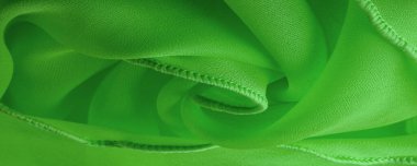 Dalgalı boruları olan yeşil ipek bir organza. Kumaşın kenarındaki sınır. Soyut arkaplan. doku deseni. İpek organzanın narin bir açık dokuması vardır. Dalga arkaplanı. Boşluğu kopyala