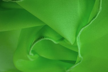 Dalgalı boruları olan yeşil ipek bir organza. Kumaşın kenarındaki sınır. Soyut arkaplan. doku deseni. İpek organzanın narin bir açık dokuması vardır. Dalga arkaplanı. Boşluğu kopyala