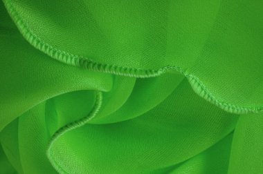 Dalgalı boruları olan yeşil ipek bir organza. Kumaşın kenarındaki sınır. Soyut arkaplan. doku deseni. İpek organzanın narin bir açık dokuması vardır. Dalga arkaplanı. Boşluğu kopyala