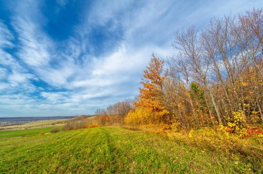 Sonbahar manzara fotoğrafçılığı, Dünya 'nın Avrupa kısmı. Günbatımında akşam gökyüzünün güzel bir gradyanı olan kırsal alan. Yeşil alan ve ufukta köy