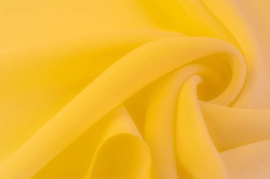 Doku. şablon. Sarı ipek polyester. Sarı ipek kumaşın arka planı. Şeffaf arkaplan ve elbise dikmek için açık kumaştan yapılmış. Tekstil panoraması.