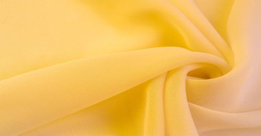 Doku. şablon. Sarı ipek polyester. Sarı ipek kumaşın arka planı. Şeffaf arkaplan ve elbise dikmek için açık kumaştan yapılmış. Tekstil panoraması.