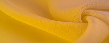 Doku. şablon. Sarı ipek polyester. Sarı ipek kumaşın arka planı. Şeffaf arkaplan ve elbise dikmek için açık kumaştan yapılmış. Tekstil panoraması.