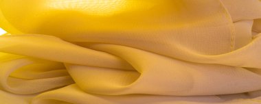 Doku. şablon. Sarı ipek polyester. Sarı ipek kumaşın arka planı. Şeffaf arkaplan ve elbise dikmek için açık kumaştan yapılmış. Tekstil panoraması.