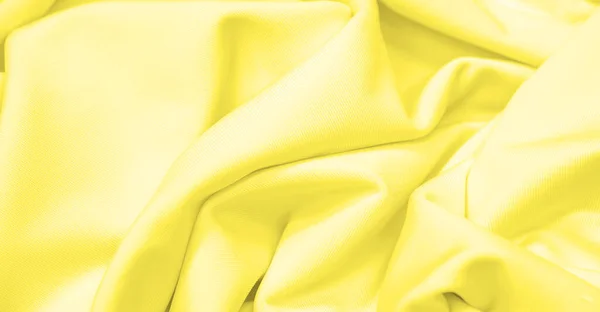 The fabric is yellow silk. Texture. Background. Pattern. Silk fabric has a shiny sheen and characteristic small folds that run horizontally. She lies down in soft folds