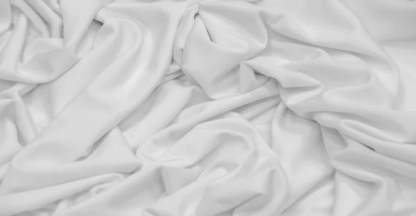 White silk fabric. Texture. Background. Pattern. Dupioni silk fabric has a shiny sheen and characteristic small folds that run horizontally. She lies down in soft folds