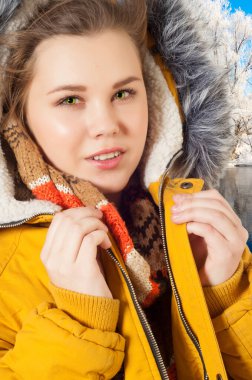 Kışlık ceketli kız. Gülümseyen Kış Kızı. Kürk kapüşonlu, sıcacık kışlık ceketli tatlı genç kız, yüzünde sevimli bir gülümsemeyle yukarı bakıyor.,