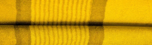 Texture. Background. Silk fabric of yellow color, of the color between green and orange in the spectrum, a primary subtractive color complementary to blue; colored like ripe lemons or egg yolks.