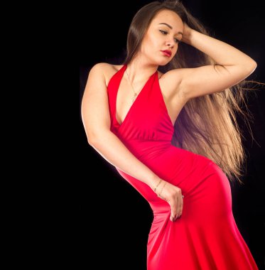 Kırmızı elbiseli güzel bir kız, güzel bir kadın model stüdyoda basit kırmızı bir elbise içinde poz veriyor.. 