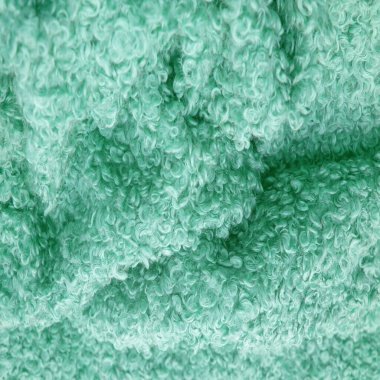 Karakul yapay koç derisi. Yeşil renk. Genç bir astrakhan (kuzu) kumaşının altında inanılmaz kalitede yapay eko-kürk. Özel tasarım, palto kumaşı, doku, arka plan, desen.