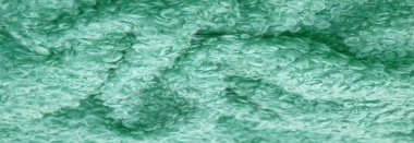 Karakul yapay koç derisi. Yeşil renk. Genç bir astrakhan (kuzu) kumaşının altında inanılmaz kalitede yapay eko-kürk. Özel tasarım, palto kumaşı, doku, arka plan, desen.