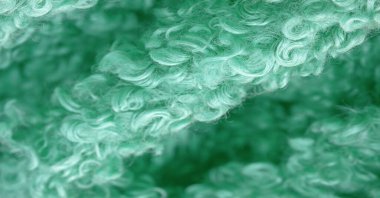 Karakul yapay koç derisi. Yeşil renk. Genç bir astrakhan (kuzu) kumaşının altında inanılmaz kalitede yapay eko-kürk. Özel tasarım, palto kumaşı, doku, arka plan, desen.