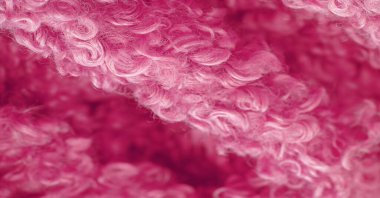 Karakul yapay koç derisi. Kırmızı renk. Genç bir astrakhan (kuzu) kumaşının altında inanılmaz kalitede yapay eko-kürk. Özel tasarım, palto kumaşı, doku, arka plan, desen.