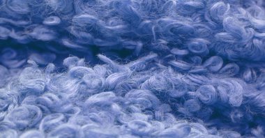 Karakul yapay koç derisi. Mavi renk. Genç bir astrakhan (kuzu) kumaşının altında inanılmaz kalitede yapay eko-kürk. Özel tasarım, palto kumaşı, doku, arka plan, desen.