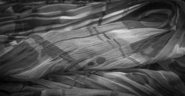 Siyah ipek kumaş, çiçek desenli. Dalgalı kıvrımlar. Kumaşın yüzeyinde ince bir dalga var. Arkaplan dokusu, dekoratif süs