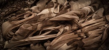 Kahverengi ipek kumaş, çiçek desenli. Dalgalı kıvrımlar. Kumaşın yüzeyinde ince bir dalga var. Arkaplan dokusu, dekoratif süs