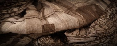 Kahverengi ipek kumaş, çiçek desenli. Dalgalı kıvrımlar. Kumaşın yüzeyinde ince bir dalga var. Arkaplan dokusu, dekoratif süs