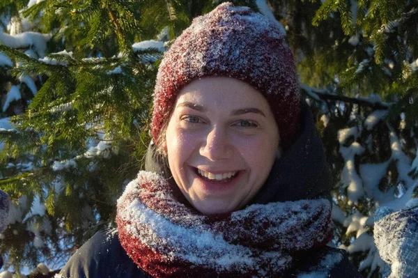 雪のモミの芝生を背景に少女の写真 ふわふわの雪 赤いニット帽 — ストック写真