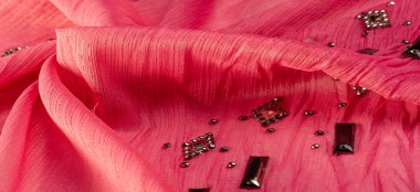 İpek desenli, kırmızı kumaş ve dekoratif yüzlü taşlar. parlak renkli taşlarla dokuma arkaplanı