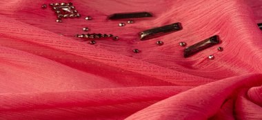 Arkaplan tasarımı dokusu, ipek desen, pembe kumaş ve dekoratif işlemeli taşlar.