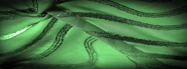 Silk fabric with green stripes. Abstract silk tones in emerald tones. Vintage pattern on the fabric. Background texture, decorative ornament
