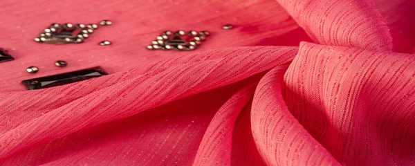 İpek desenli, kırmızı kumaş ve dekoratif yüzlü taşlar. parlak renkli taşlarla dokuma arkaplanı