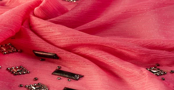 İpek desenli, kırmızı kumaş ve dekoratif yüzlü taşlar. parlak renkli taşlarla dokuma arkaplanı