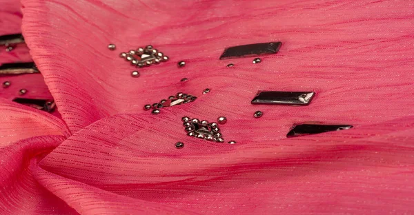 İpek desenli, kırmızı kumaş ve dekoratif yüzlü taşlar. parlak renkli taşlarla dokuma arkaplanı, doku arkaplan tasarımı